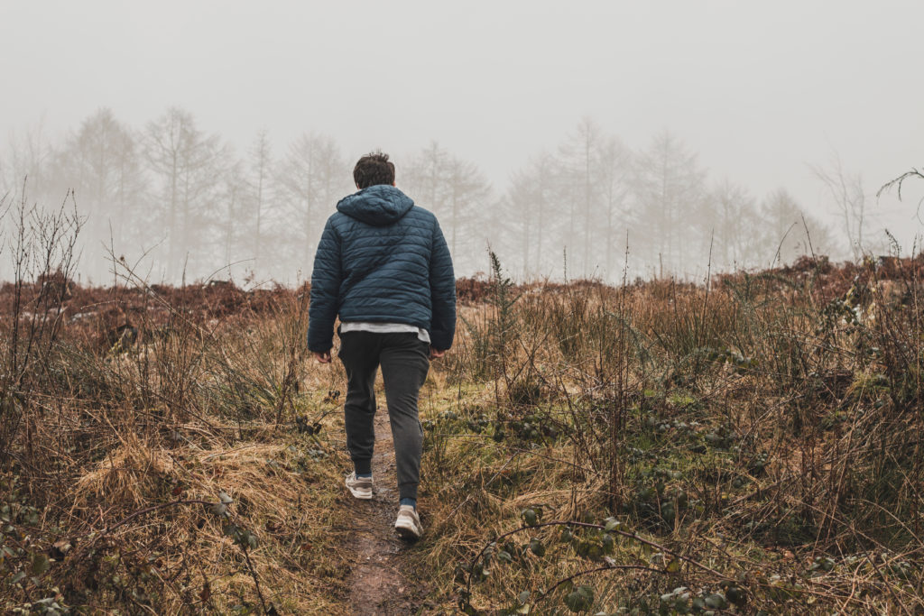 Man in Blue Hoody walking through a field