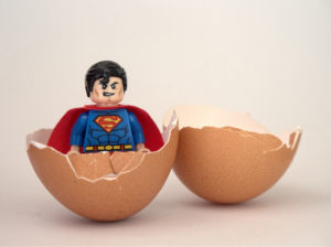 Superman figurine standing in a broken half eggshell